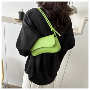 Detailed view of a green underarm bag featuring a wave flap and knotted shoulder strap
