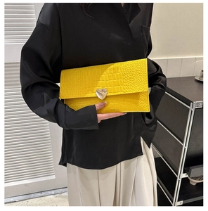 Close-up of bright yellow crocodile embossed clutch bag with heart silver buckle