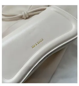 Detailansicht der glatten beigen Lederstruktur und des goldgeprägten XM & BAGS Logos