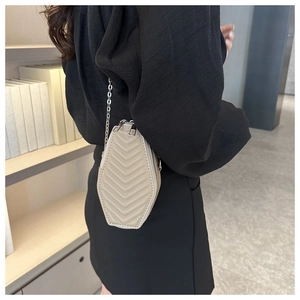 Close-up of beige quilted crossbody bag with silver chain strap and chevron pattern