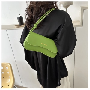 Detail of trendy grass green underarm bag with knot strap and gold logo lettering