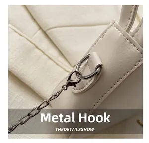 Close-up of cream leather bag showing silver hardware hook and neat stitching detail