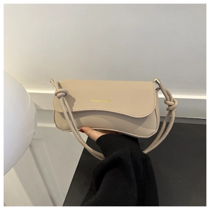 Detail of beige matte leather crossbody bag featuring knot strap and gold fashion logo