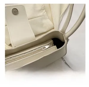Detail view of smooth silver metal zipper and textured cream leather of the handbag