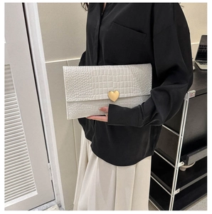 Detailed close-up of white crocodile pattern envelope clutch with gold heart-shaped buckle