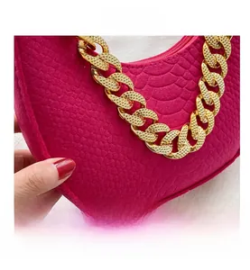 Detailed close-up of rose red faux snakeskin texture and thick gold chain strap on the handbag
