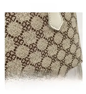 Macro view of beige shell bag fabric with brown clover pattern and precise stitching