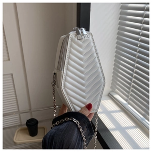 Detailed view of white coffin-shaped crossbody bag with V-quilted faux leather and silver chain