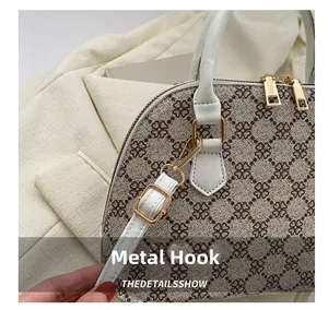 Detailed close-up of golden metal hooks and clover pattern on stylish crossbody shell bag