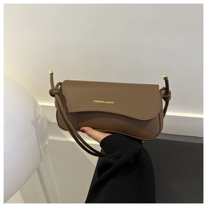 Detail showing the magnetic closure and knot shoulder strap of the brown leather bag