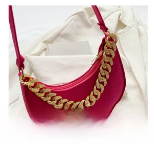 Detail of magenta hobo bag with crocodile texture and chunky gold chain on white blazer