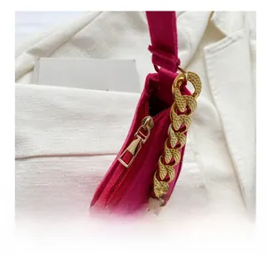 Close-up of smooth metal zipper and gold chain strap on rose pink crocodile bag