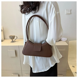 Brown faux leather baguette bag shown as a shoulder bag on a model in a minimalist setting