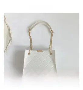 Close-up of a white quilted felt crossbody bag with golden chain strap and leather handle