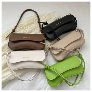 Flat lay of multiple stylish leather shoulder bags in five colors on a draped fabric