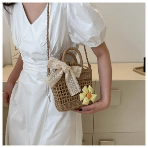 Strohhandtasche mit Spitzenschleife und Blumenanhänger von Model im Heimsetting