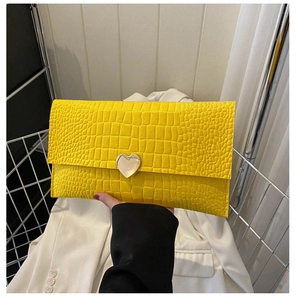 Detail of yellow crocodile pattern envelope clutch with heart shaped silver buckle