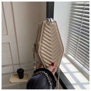 Detail of beige chevron quilted hexagonal crossbody bag with silver chain strap and zipper