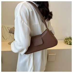 Detail of brown faux leather rectangular handbag with magnetic strap closure and shoulder strap