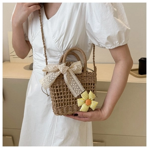 Detail der gewebten Strohhandtasche mit Spitzenschleife und Sonnenblumen-Anhänger