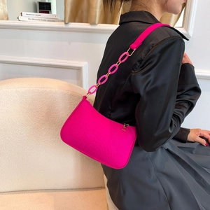 Hot pink embossed leather crossbody bag with matching chain strap shown on a model