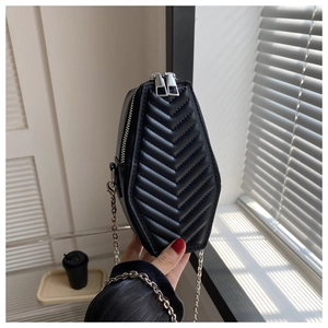 Close-up of black coffin shaped crossbody bag with chevron stitching and silver chain
