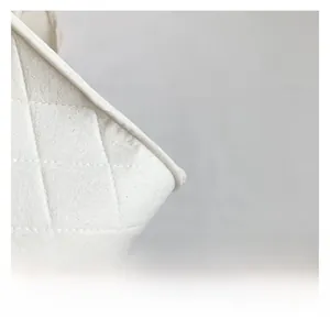 Detailed close-up of white felt crossbody bag featuring classic quilted diamond stitching