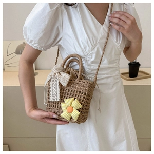 Detail der gewebten Strohtasche mit karierter Blume und Spitzenschleife auf weißem Kleid