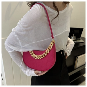 Detail of rose red crescent bag with chunky gold chain decoration and leather texture