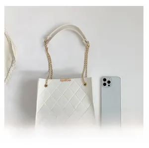 Detail of white felt quilted shoulder bag with gold chain strap and metal clasp