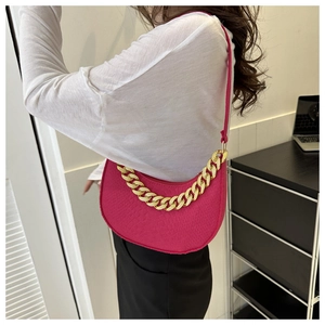 Detail of rose red crescent bag featuring gold chain and animal skin texture pattern