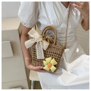 Detail der handgewebten Strohtasche mit zarter Spitzenschleife und karierter Sonnenblume