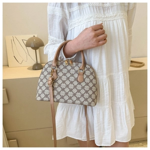 Detail of shell-shaped crossbody bag with clover pattern and brown leather straps