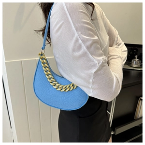 Detail of blue hobo bag with grainy leather texture and gold chain decoration