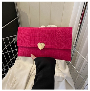 Detail view of pink crocodile pattern envelope clutch bag with gold heart buckle