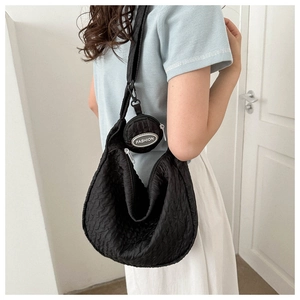 Detail of black pleated crossbody bag with matching round coin purse and fashion tag