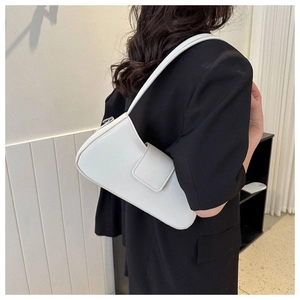 Minimalist white leather baguette bag worn over the shoulder with a black blazer