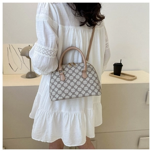 Detail of vintage patterned shell bag worn by model in a minimalist creamy interior