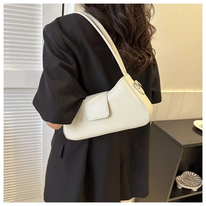 Close-up of off-white minimalist shoulder bag with flap design worn by a model