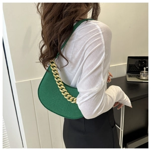 Detail of green faux crocodile texture hobo bag with a thick gold chain handle