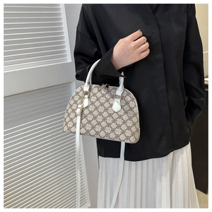 Detail of beige dome satchel bag featuring clover pattern and white leather handles