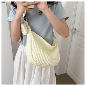 Detail view of cream-colored pleated hobo bag with matching round coin purse on shoulder strap