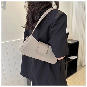 Minimalist beige underarm bag detail showing flap closure and smooth shoulder strap