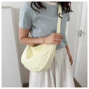 Detail of the bubble texture and adjustable strap on a yellow crossbody crescent bag