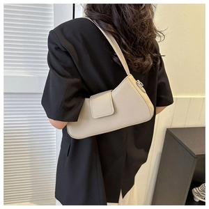 Detail showing beige baguette bag on model shoulder with minimalist leather finish