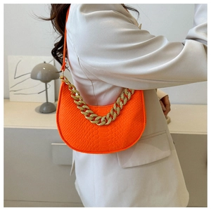 Detail of bright orange faux crocodile leather crescent bag with bold gold chain strap