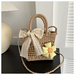 Detail der Strohtasche mit Spitzenschleife und Karoblume sowie langem Schultergurt