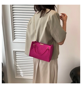 Detail of fuchsia felt crossbody bag with golden chain and diamond quilted pattern