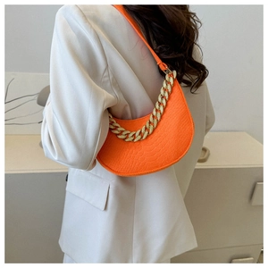 Detail of bright orange faux crocodile leather crescent bag with gold chain strap