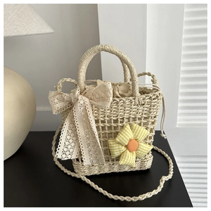 Detail der gewebten Strohtasche mit Spitzenschleife und floralem Akzent für Damen